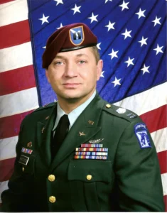 Soldier in uniform with American flag background.