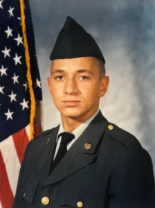 Young soldier in uniform with American flag.