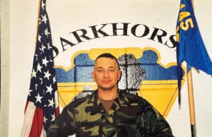 Soldier posing between flags, "Darkhorse" background.