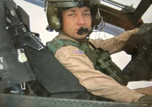 Pilot in cockpit wearing flight helmet.