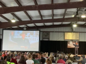 Audience watching a speaker on stage indoors.