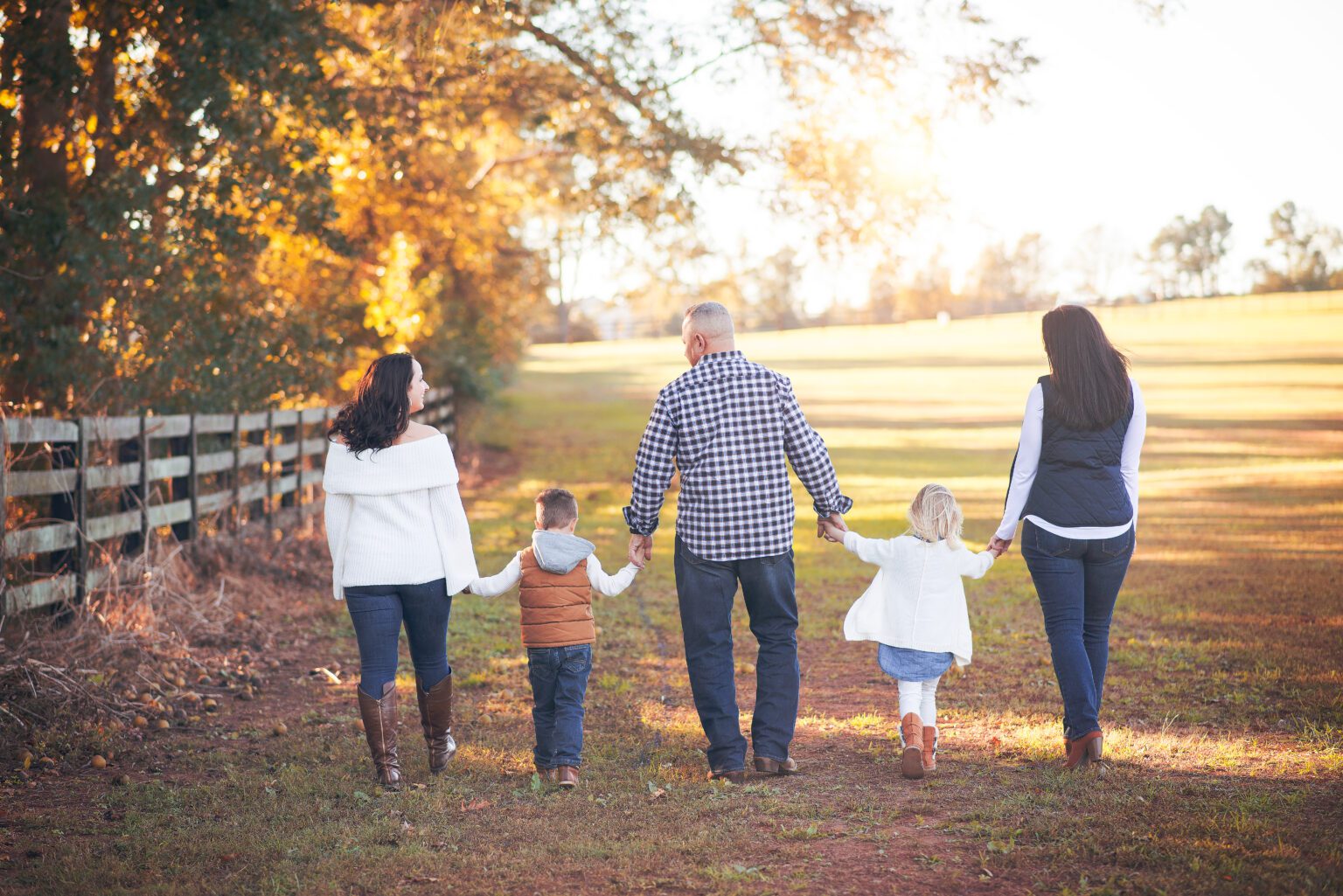 Family holding hands and walking in a park during autumn.